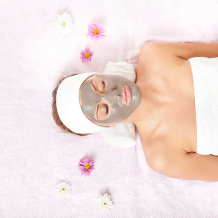 Young woman relaxing with clay skin mask on her faceの写真素材