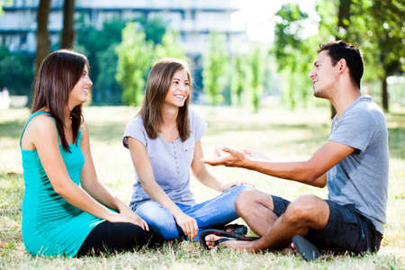 Happy friends talking in park on a summer dayの写真素材