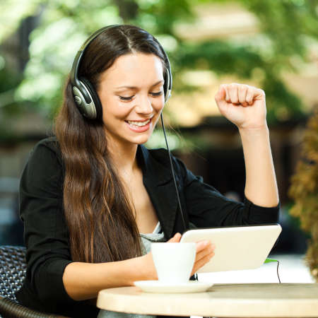 Young woman using tablet and listening music in cafeの写真素材