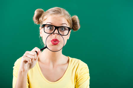 Nerdy student with loupe in front of blackboardの写真素材