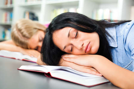 Tired students sleeping in libraryの写真素材
