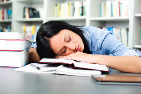 Tired student sleeping in libraryの写真素材