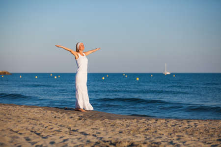 Happy young woman standing on the beach with arms outstretchedの写真素材