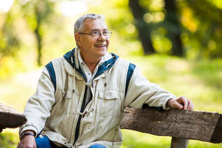 Happy senior man sitting on bench in parkの写真素材