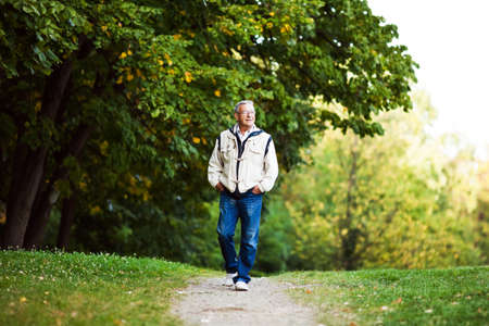 Happy senior man walking and relaxing in parkの写真素材