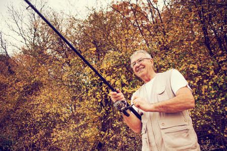 Happy senior man fishing, intentionally toned.の写真素材