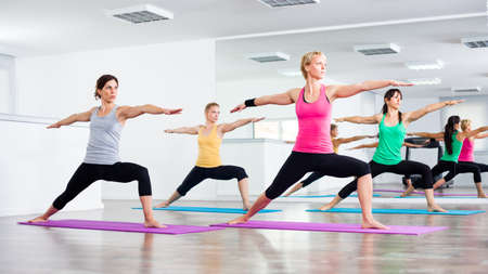Four girls practicing yoga, Yoga - Virabhadrasana Warrior poseの写真素材