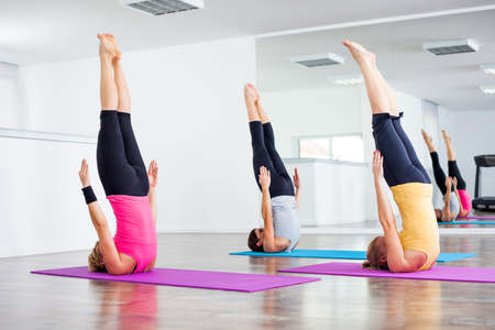 Three girls practicing yoga, Yoga Sarvangasana Shoulder stand poseの写真素材