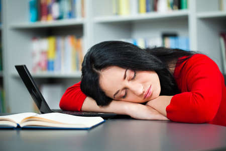 Tired student sleeping in libraryの写真素材