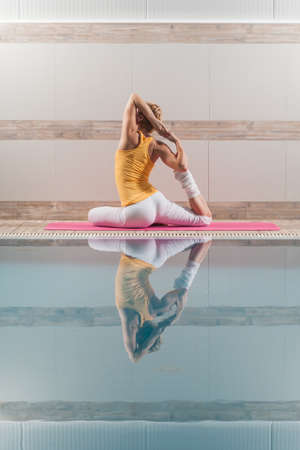 Young woman practicing yoga at swimming pool, Eka pada Rajakapotasana Pigeon poseの写真素材