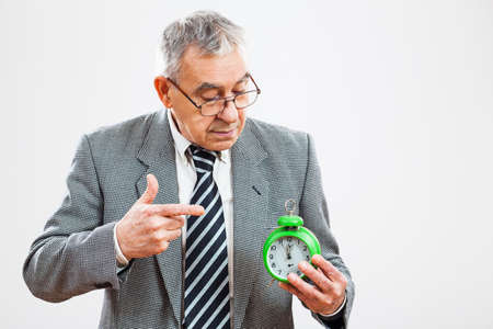 Senior businessman pointing at clock that shows five to twelve time
