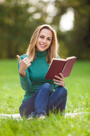 Young woman is reading a book in parkの写真素材