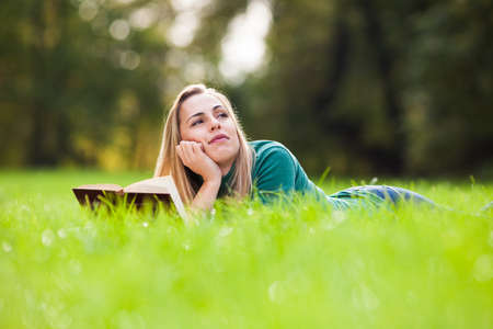Young woman is reading a book in parkの写真素材