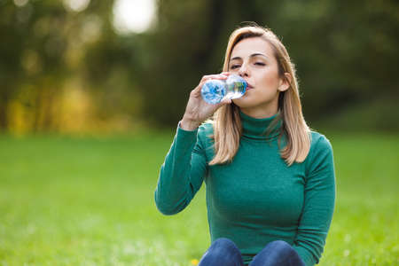 Young woman drinking water in parkの写真素材