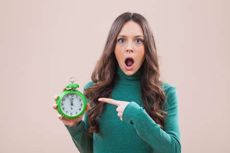 Woman holding clock that shows five to twelve timeの写真素材