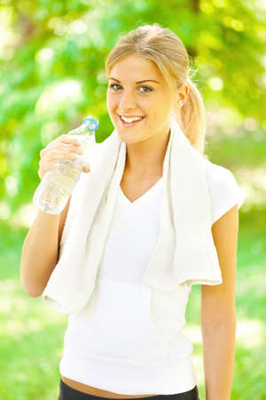 Young woman is drinking water after joggingの写真素材