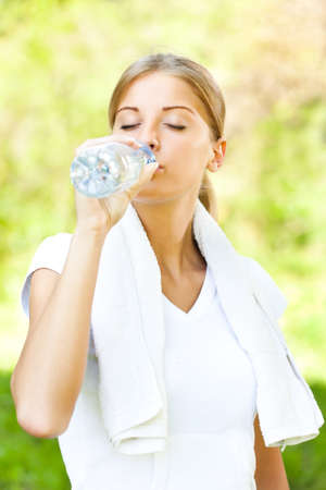 Young woman is drinking water after joggingの写真素材