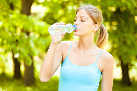 Young woman is drinking water after joggingの写真素材