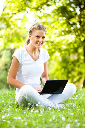 Young woman is using laptop in park.の写真素材