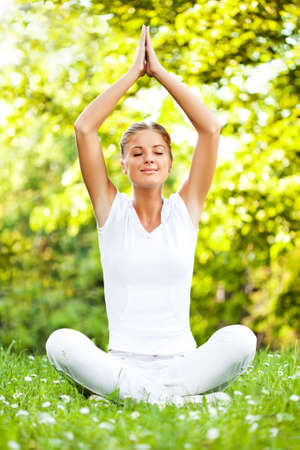 Young woman is meditating in park.の写真素材