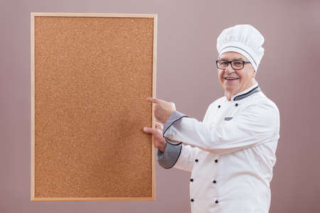 Portrait of restaurant's chef in working uniform showing what is on menuの写真素材