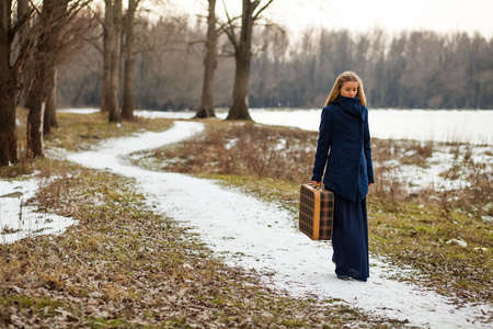 Woman walking in forest with old suitcaseの写真素材
