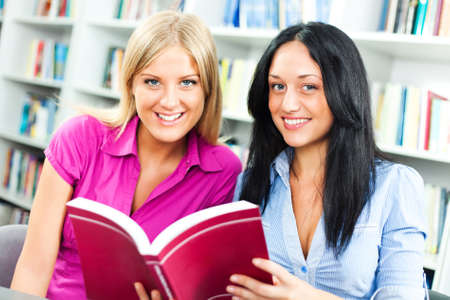 Happy students learning in library, reading a book.の写真素材