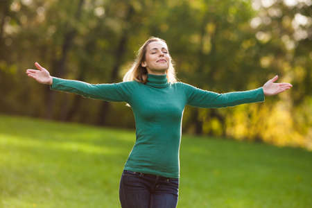 Happy woman standing in park and enjoying natureの写真素材