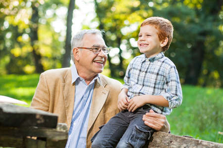 Grandfather and grandson sitting and talking in park