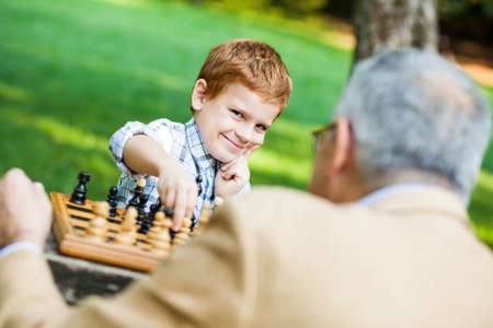 Grandfather and grandson are playing chess in parkの写真素材