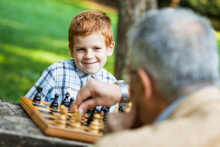 Grandfather and grandson are playing chess in parkの写真素材
