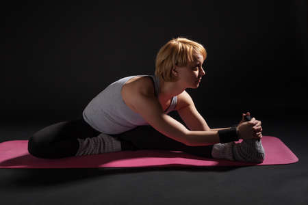 Young woman practicing yoga, Upavistha Konasana / Wide Angle Seated Forward Bend pose