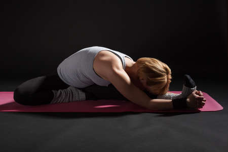 Young woman practicing yoga, Upavistha Konasana / Wide Angle Seated Forward Bend poseの写真素材