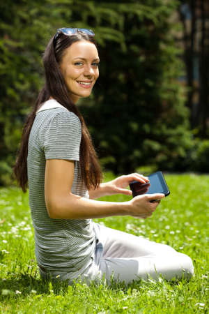 Young happy woman is using tablet in park.