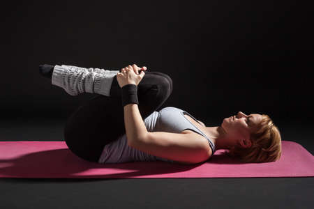 Young woman practicing yoga, Pawanmuktasana / Wind Relieving pose