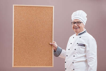 Portrait of restaurant's chef in working uniform showing what is on menuの写真素材
