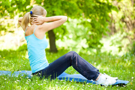 Young woman is exercising in park. She is stretching her body.の写真素材