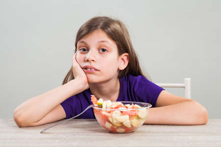 Little girl does not like to eat fruit salad.の写真素材