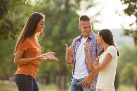 Three friends are standing in park and talking.の写真素材