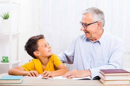 Grandfather is teaching his grandson at home.の写真素材