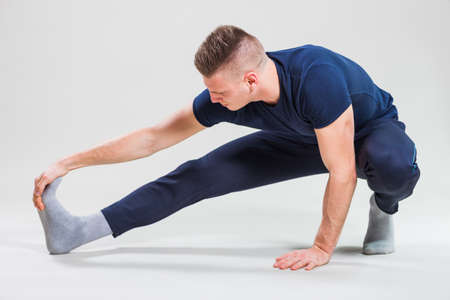 Studio shot image of young man who is stretching his body.
