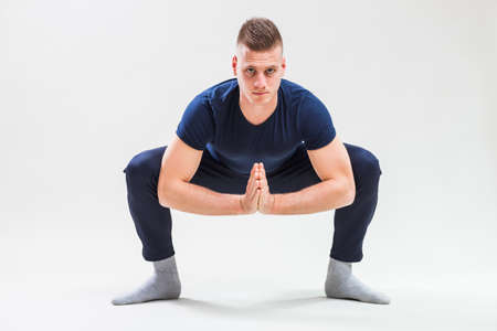 Studio shot image of young man who is stretching his body. Utatasana / Buddhist stupa pose