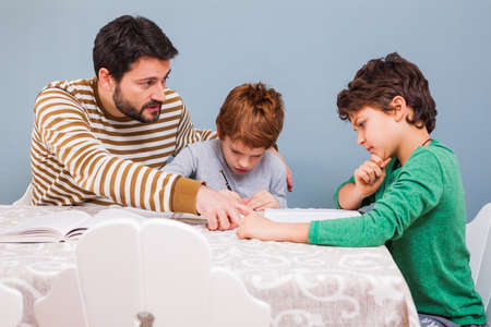 Father is doing homework with his sons.の写真素材
