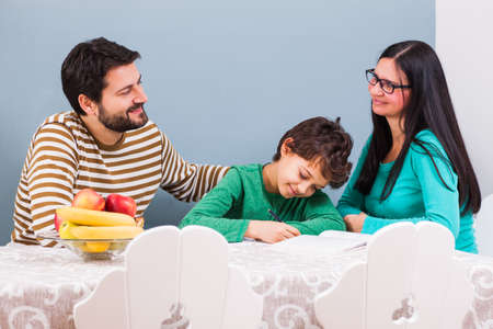 Parents are teaching their son at home.の写真素材
