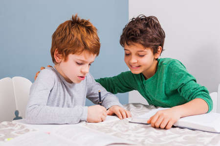 Brothers are doing homework together at home.の写真素材