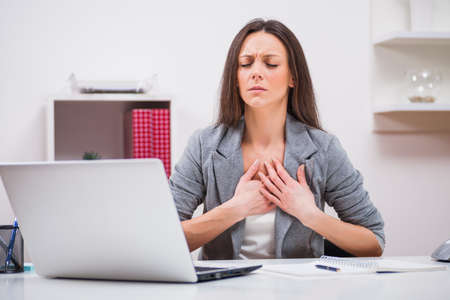 Young businesswoman is having pain in her chest at work.の写真素材