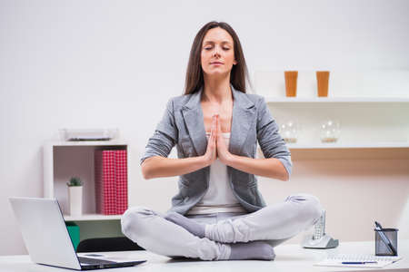Young businesswoman is meditating in her office.の写真素材