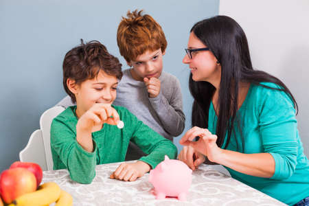 Mother is teaching her sons how to save money.の写真素材