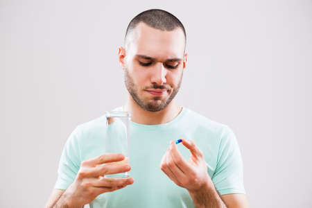 Portrait of young man who is taking a pill because of illness.の写真素材