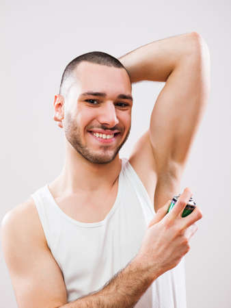 Young man is applying antiperspirant to his armpit.の写真素材